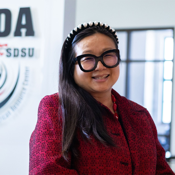 smiling woman with long dark wearing glasses